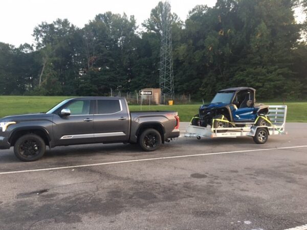 An all aluminum trailer loaded with an UTV being pulled by a truck.