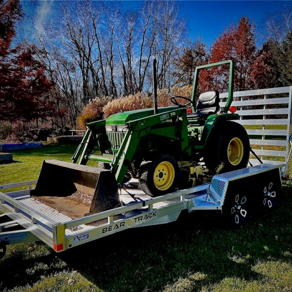 An all aluminum trailer with a straight ramp, loaded with a tractor.