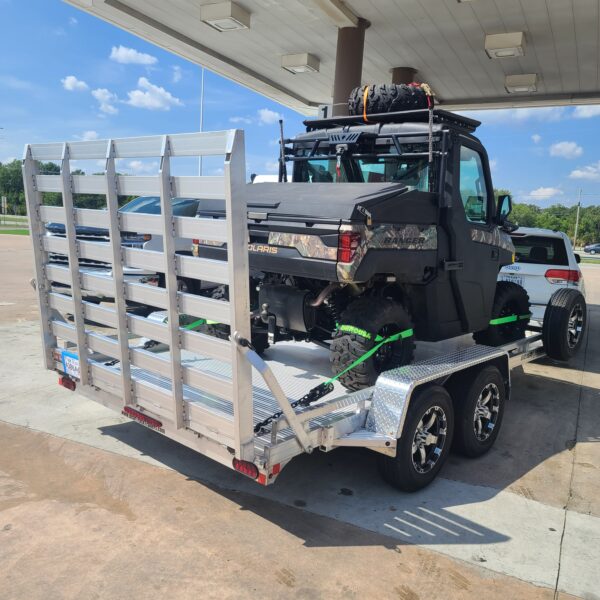 An all aluminum trailer with a straight ramp loaded with an UTV, getting pulled by a van.